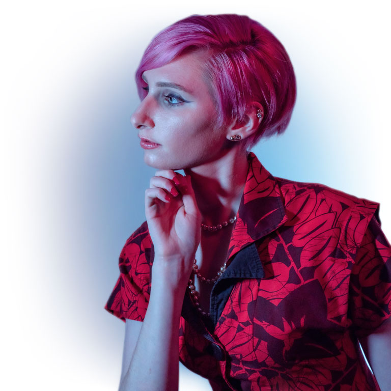 Kate Durr looks to the side. Pink hair, red dress, and blue background.